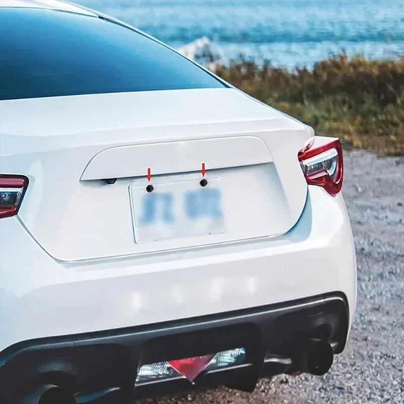 White car with a blurred license plate and red lights on a gravel road with ocean view