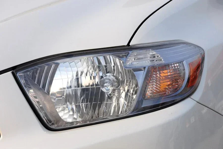 Close-up of a car headlight on a white vehicle