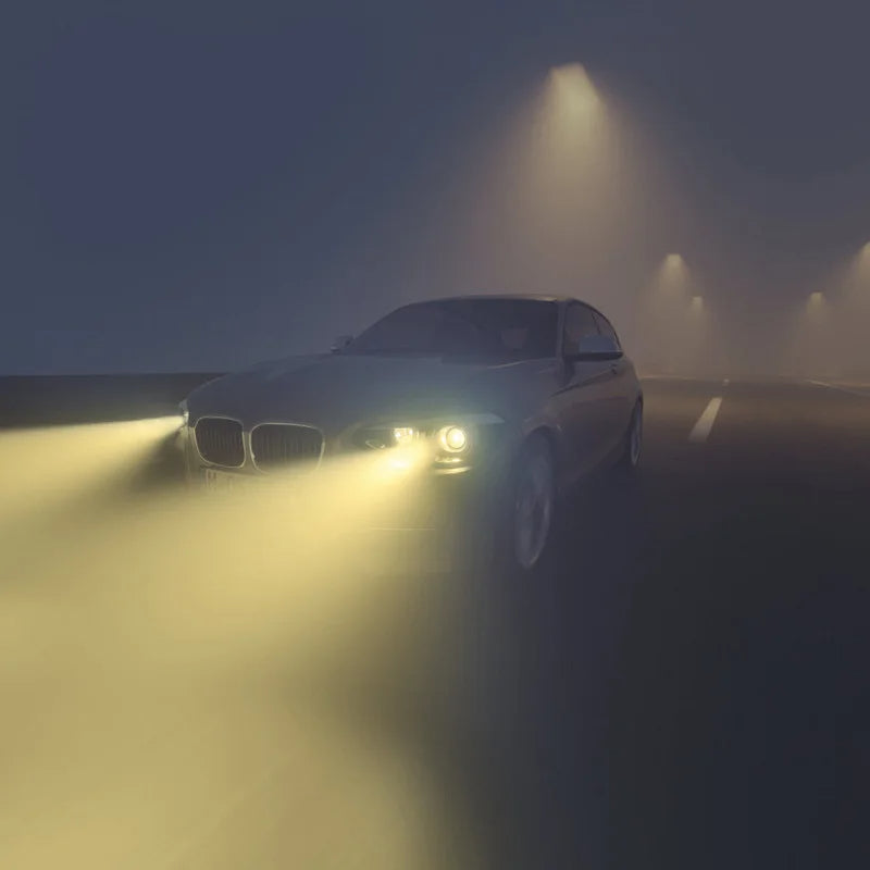 Car driving on a foggy road with headlights illuminating the path