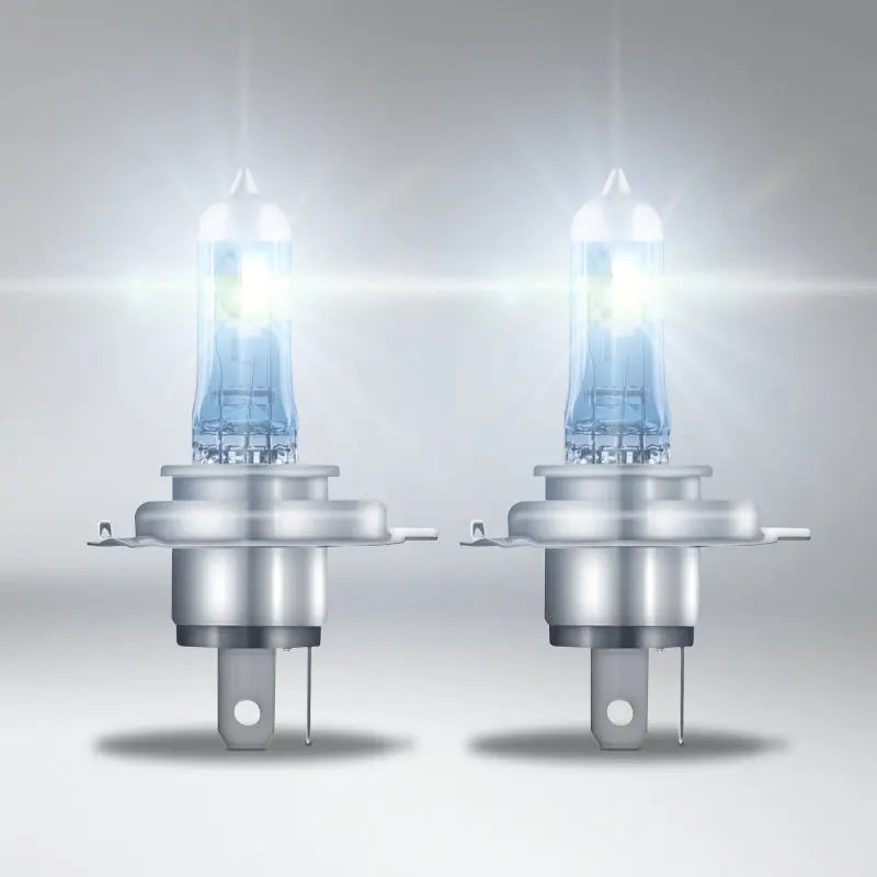 Two illuminated car headlights on a gray background