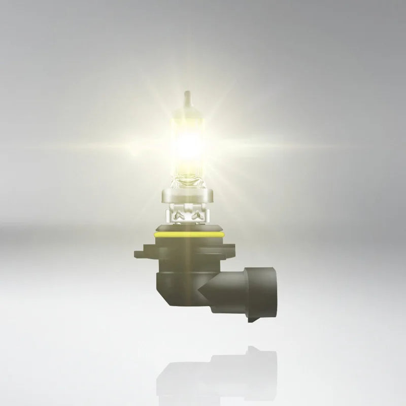 Car headlight bulb on a reflective surface with a light gray background