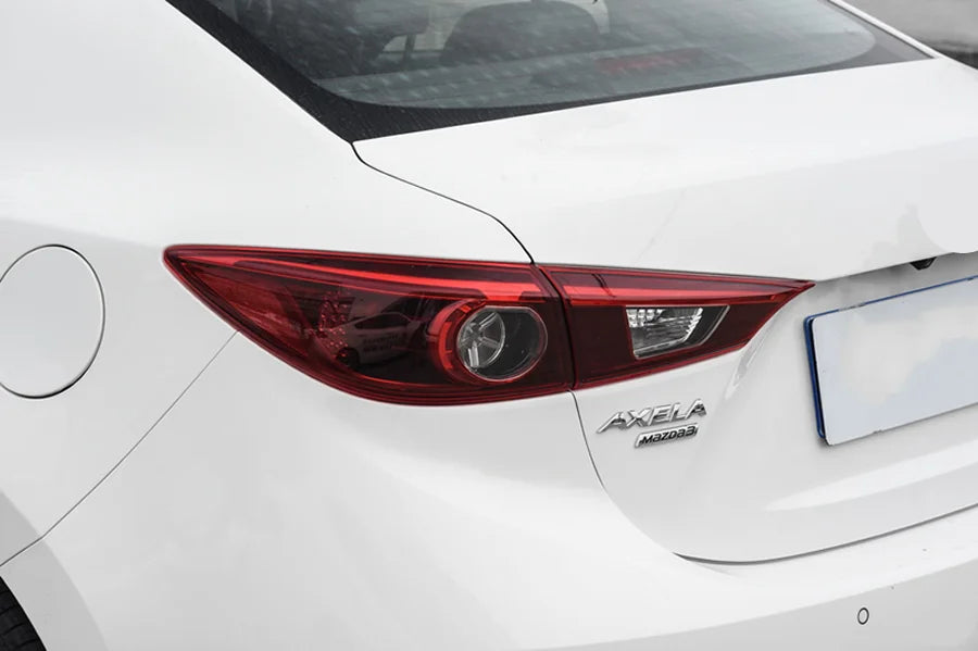 Close-up of a white car's rear end with 'Axela' branding.
