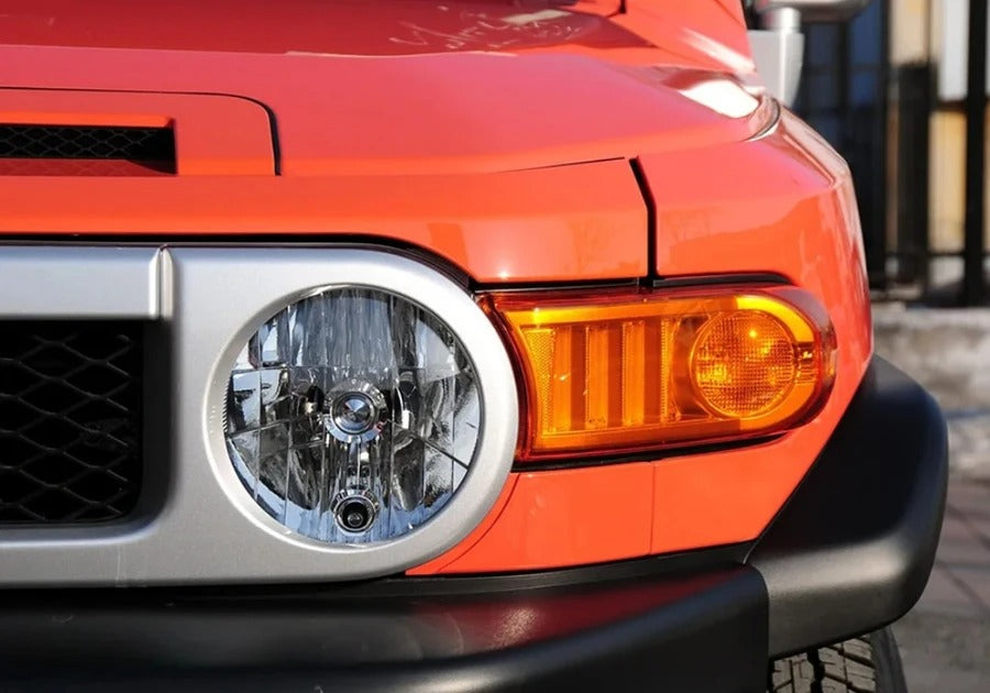 Close-up of an orange vehicle's headlight and grille