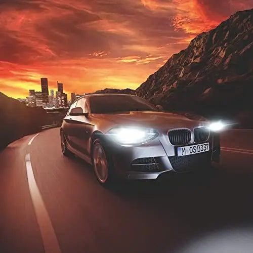 Car driving on a road with a cityscape and mountainous background during sunset.